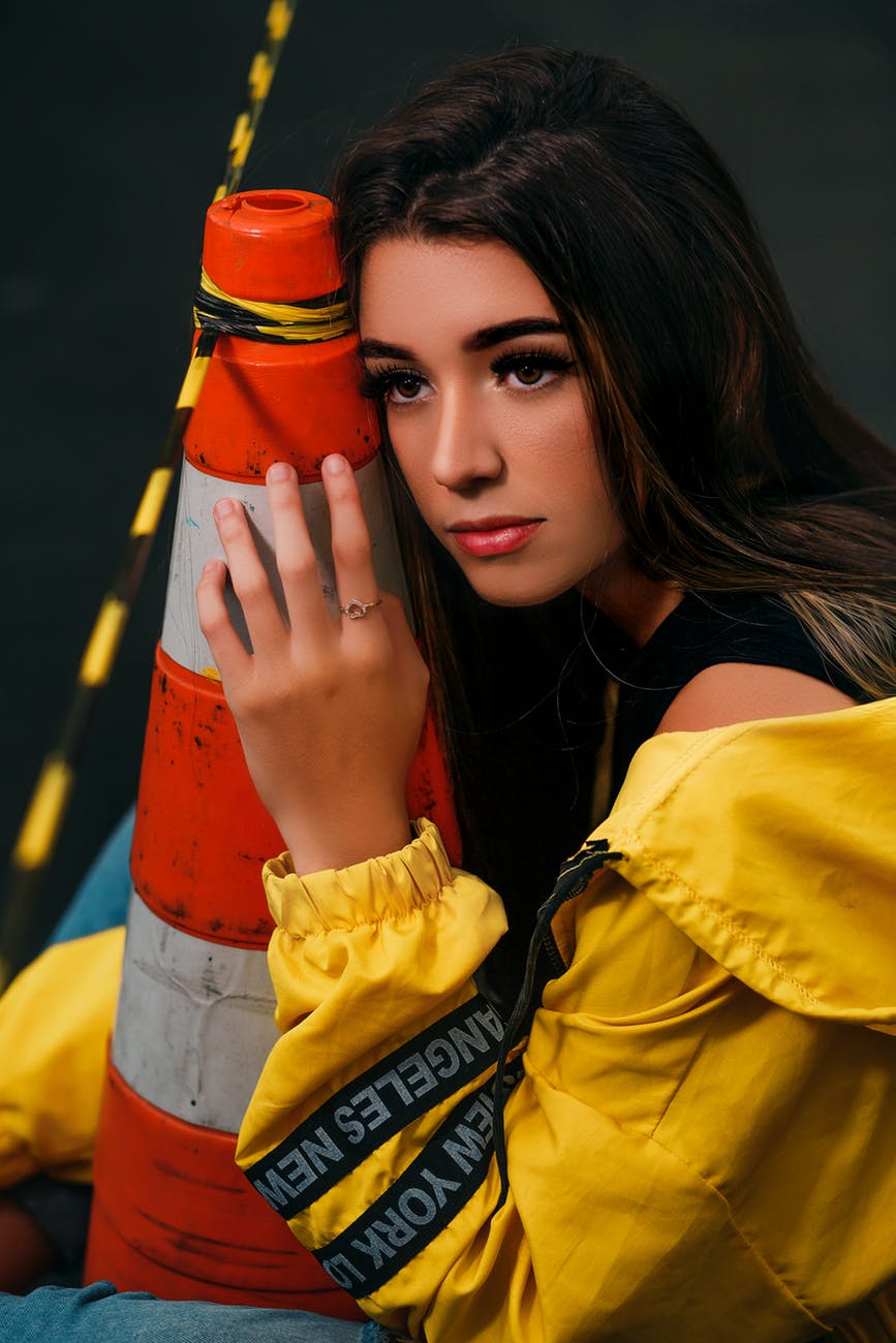 woman in yellow jacket holding a traffic cone